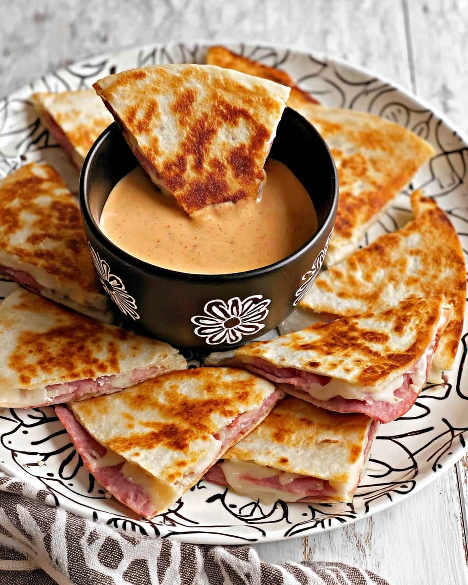 The image shows a white plate with black leaf patterns filled with several triangular quesadilla pieces. Each quesadilla slice has two golden brown toasted layers of crispy flatbread with a pinkish slice of meat and white melted cheese in between. In the center of the plate, there is a black bowl with white flower outlines filled with an orange creamy dip. Two quesadilla triangles are dipped halfway inside this bowl. The plate sits on a surface with a white marbled texture, and part of a striped cloth is visible at the bottom edge. photo taken with an iphone --ar 4:5 --v 7
