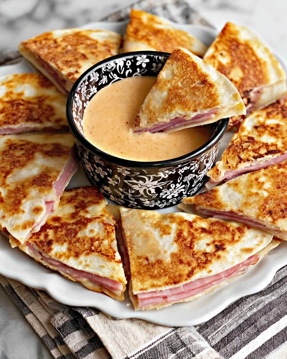 The image shows a white plate with black floral designs filled with triangular quesadilla pieces arranged around a black bowl with white floral patterns. Each quesadilla slice has two layers: a golden brown toasted outer layer with a slightly crisp texture, and a visible pink ham layer inside. The bowl in the center contains a creamy, light orange dip, and one triangular quesadilla piece is partly dipped in the sauce. The scene is set on a white marbled surface with a striped cloth partly visible at the bottom. Photo taken with an iphone --ar 4:5 --v 7