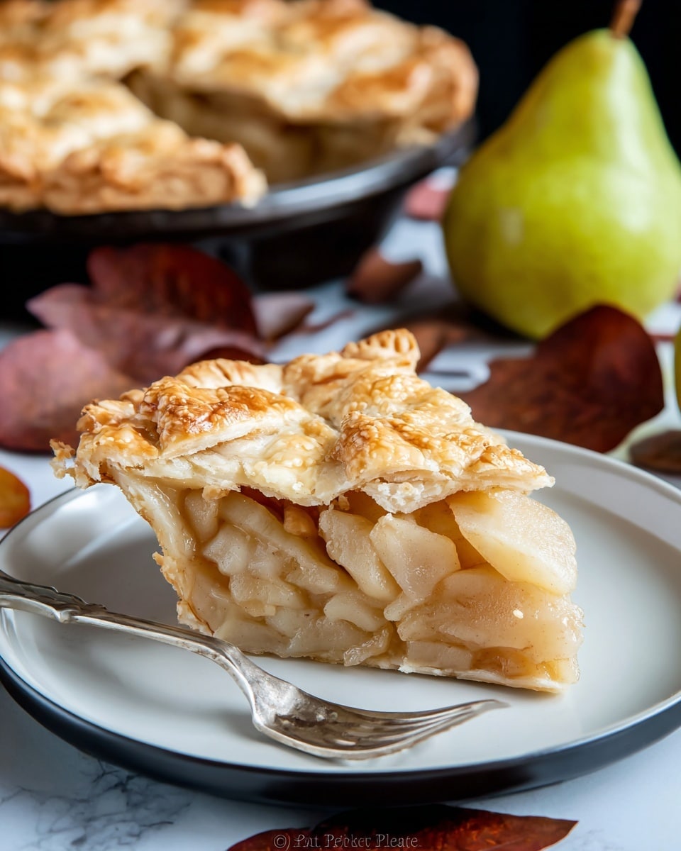 A slice of pear pie sits on a white plate, showing three distinct layers: the bottom crust is golden and firm, the middle layer is thick with soft, sliced pears in a clear syrup, and the top layer is a flaky, golden crust with a few cracks revealing the pear filling beneath. In the background, a whole pie with a crimped edge and golden top crust is visible on a white pie dish. There is a green pear and some dark brown autumn leaves near the pie slice, all on a white marbled surface. Photo taken with an iphone --ar 4:5 --v 7