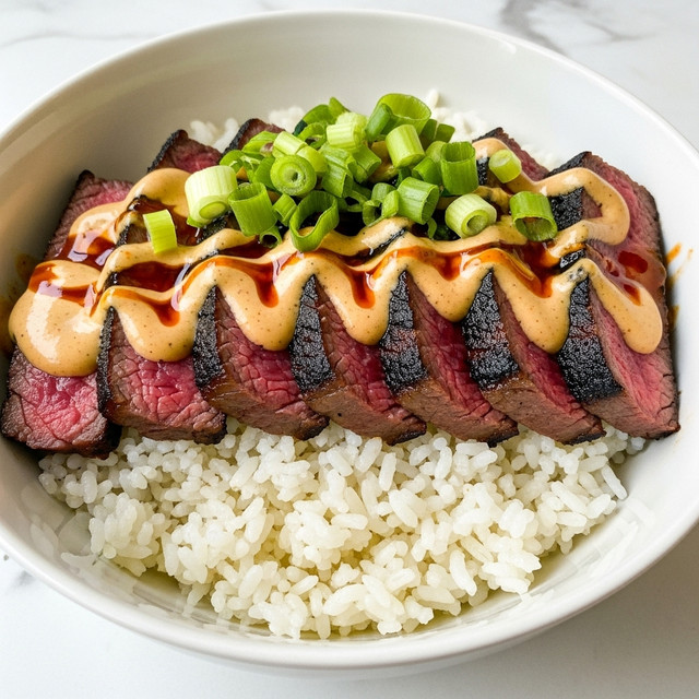 The dish shows a bowl layered with white rice at the bottom, topped with slices of grilled steak that have a charred, crispy brown crust and a juicy pink center. Over the steak, there is a creamy white sauce drizzled with a reddish-orange spicy oil. Small pieces of chopped green onions are scattered on top, adding a fresh green color. The bowl is white and it sits on a white marbled surface. photo taken with an iphone --ar 4:5 --v 7