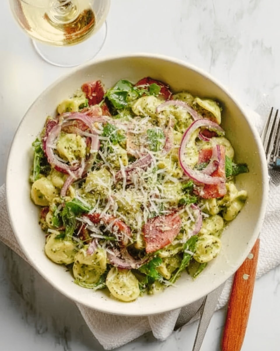 A white bowl filled with a fresh pasta salad that has three main layers: the bottom layer is green pasta shaped like small spirals, the middle layer has thin slices of pink and white ingredients, possibly prosciutto and red onion, and the top layer is sprinkled with shredded white cheese and green herbs. The bowl sits on a white marbled surface next to a silver fork with a wooden handle and a glass of white wine. A woman's hand is holding the bowl from the side. The light is soft and natural. photo taken with an iphone --ar 4:5 --v 7