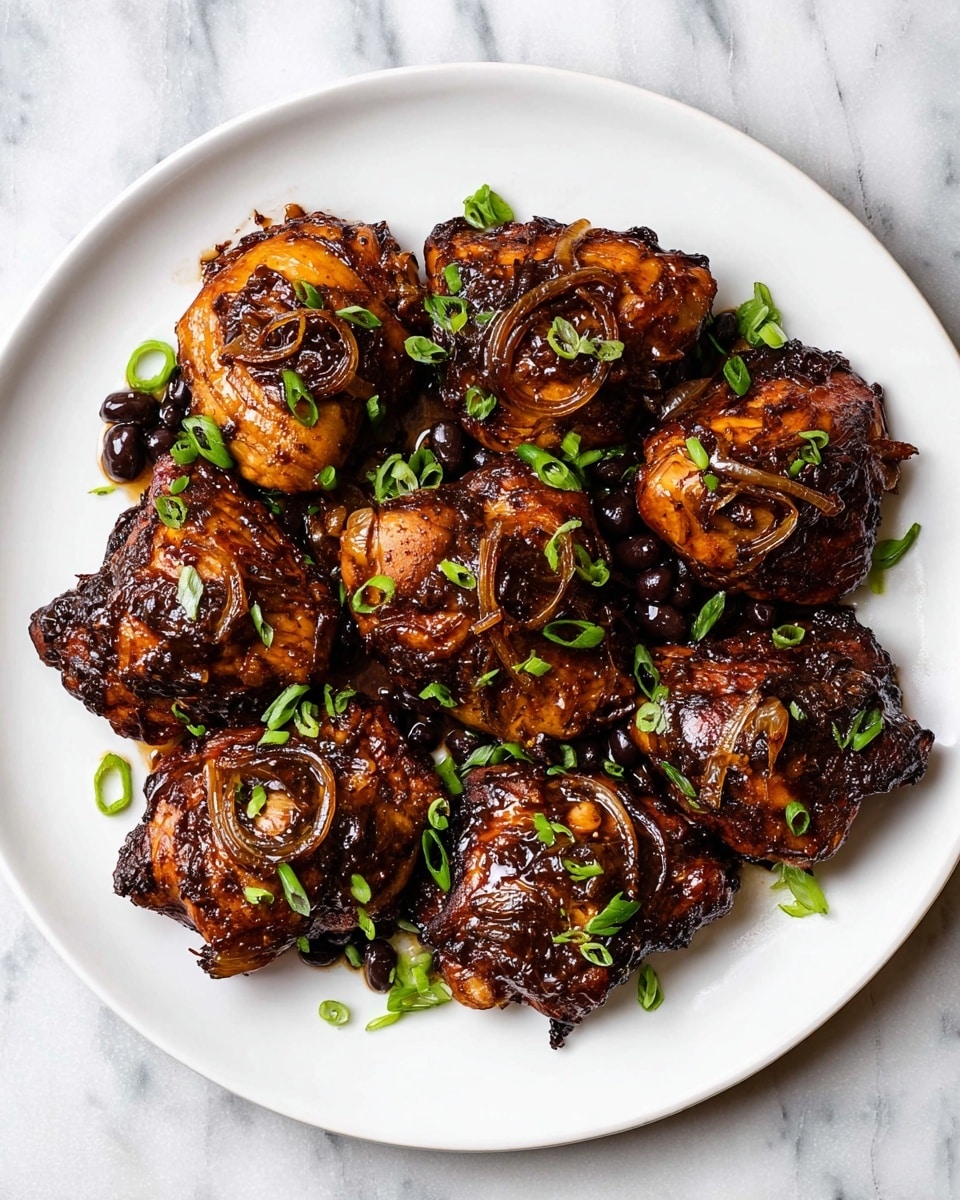 A white plate holds around nine pieces of glazed dark brown chicken thighs, each with a shiny, slightly sticky texture from a thick sauce coating. The sauce pools visibly beneath the chicken, with caramelized bits of onions and black beans spread evenly over the chicken pieces. Bright green chopped scallions are sprinkled on top, adding a fresh contrast to the rich dark brown color of the chicken. The plate is set on a white marbled surface, and the image is well-lit from above to highlight the glossy chicken skin and saucy details. photo taken with an iphone --ar 4:5 --v 7