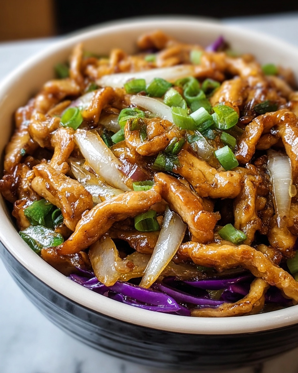 A close-up of a black bowl filled with stir-fried meat pieces that are golden brown and slightly crispy, mixed with translucent white and purple onion slices, and topped with small chopped green onions. The bowl sits on a white marbled surface. photo taken with an iphone --ar 4:5 --v 7