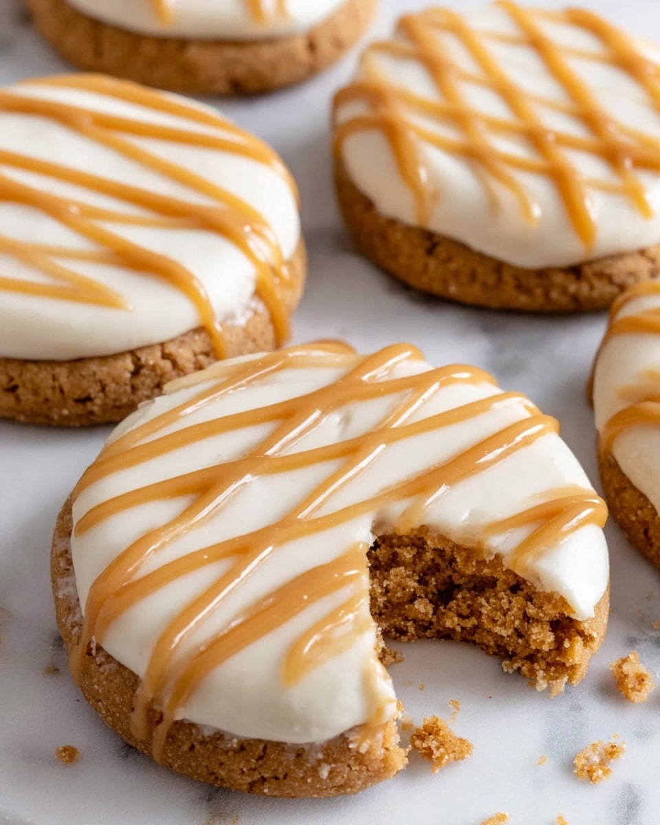The image shows five round cookies with a golden-brown base layer that looks soft and crumbly. Each cookie is topped with a thick, smooth layer of white cream evenly spread across the top. On this cream layer, there are shiny caramel-colored drizzles, applied in wavy lines from one side to the other. One cookie in the center has a bite taken out of it, revealing the fluffy texture of both the cookie and the cream. The cookies rest on a flat white marbled surface with some cookie crumbs scattered around. Photo taken with an iphone --ar 4:5 --v 7