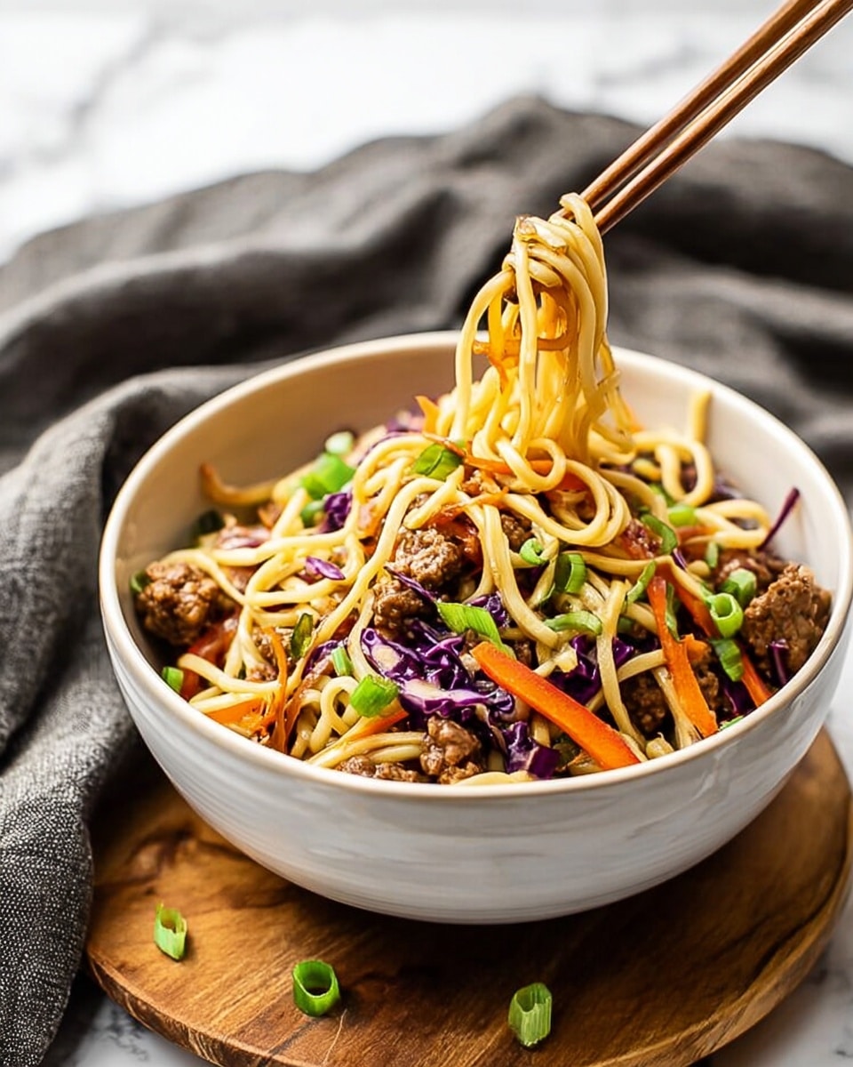 A white bowl filled with three layers: the bottom layer has light golden noodles, the middle layer shows mixed vegetables like thin orange carrot strips and purple cabbage pieces, and the top layer is scattered with small brown cooked meat chunks and bright green chopped scallions. Two wooden chopsticks hold a small bundle of noodles lifted above the bowl on the right side. The bowl is placed on a wooden board with a gray cloth loosely draped in the background over a white marbled surface. Photo taken with an iphone --ar 4:5 --v 7